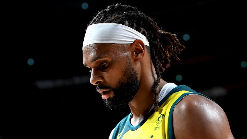 An Australian male basketballer looks towards the floor during a game at the Tokyo Olympics.