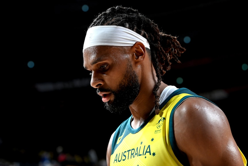 An Australian male basketballer looks towards the floor during a game at the Tokyo Olympics.
