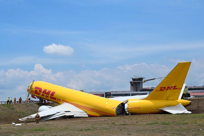 A large cargo plane sits on grass, with its tail section broken off, exposing cargo inside.
