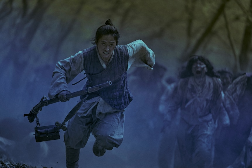 A young Korean man runs from a pack of zombies