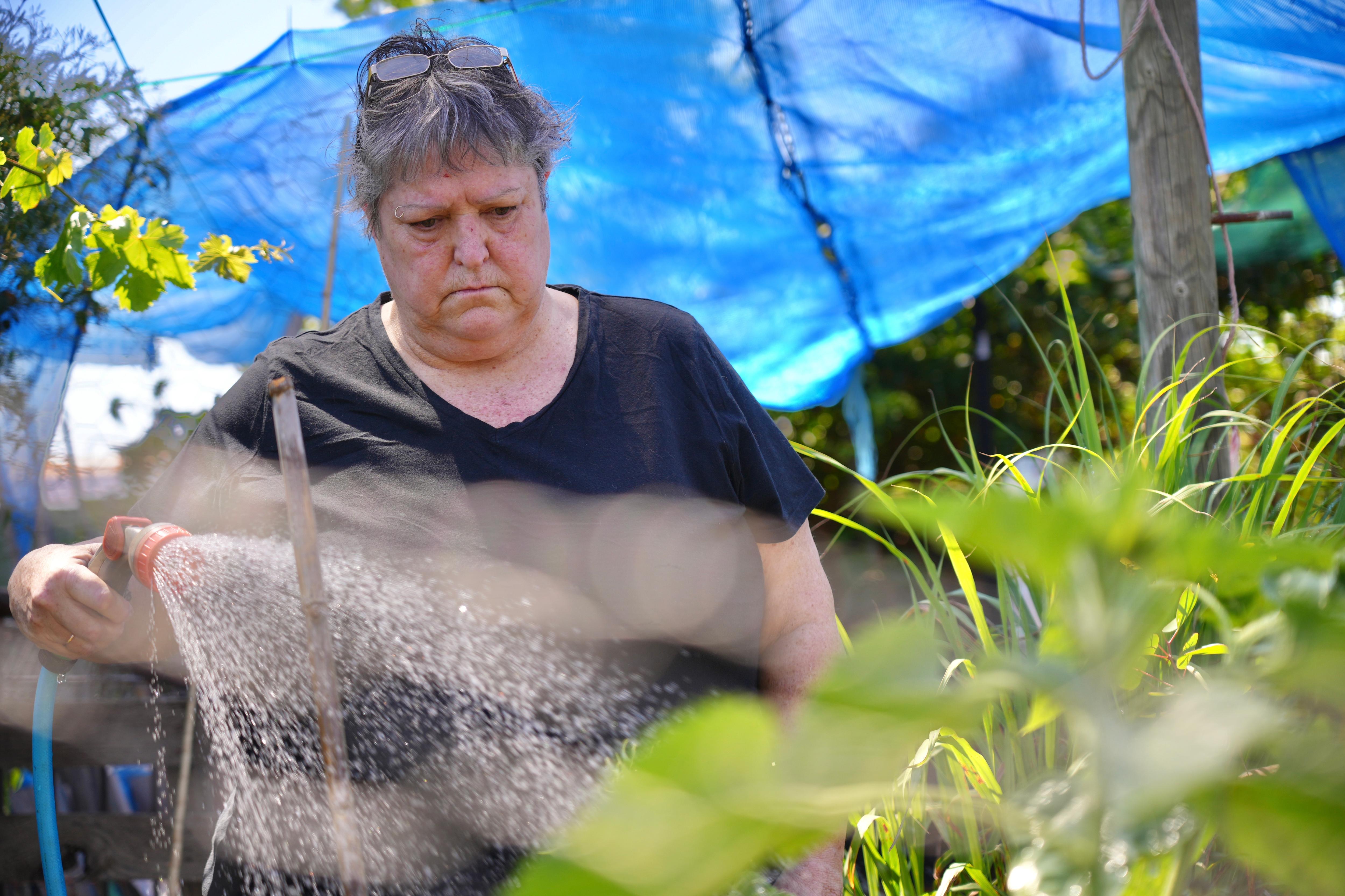 A woman waters her garden.