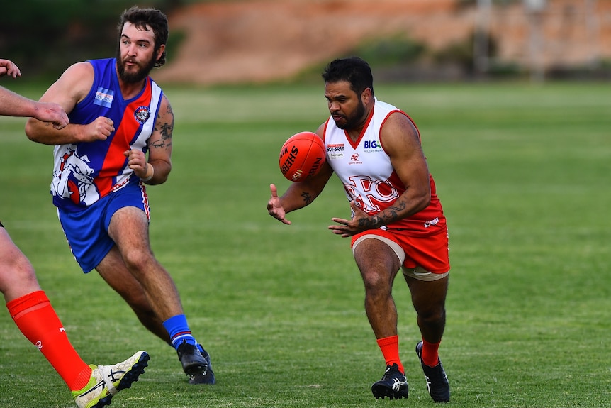 A man wearing a red and white football uniform trying to catch a ball in front of him. 