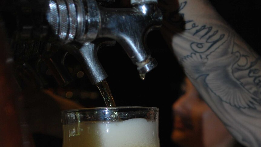 A barwoman pours a beer in a Darwin hotel.