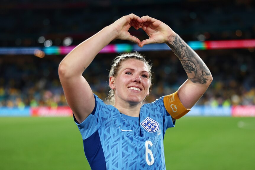 Millie Bright makes a heart shape with her hands