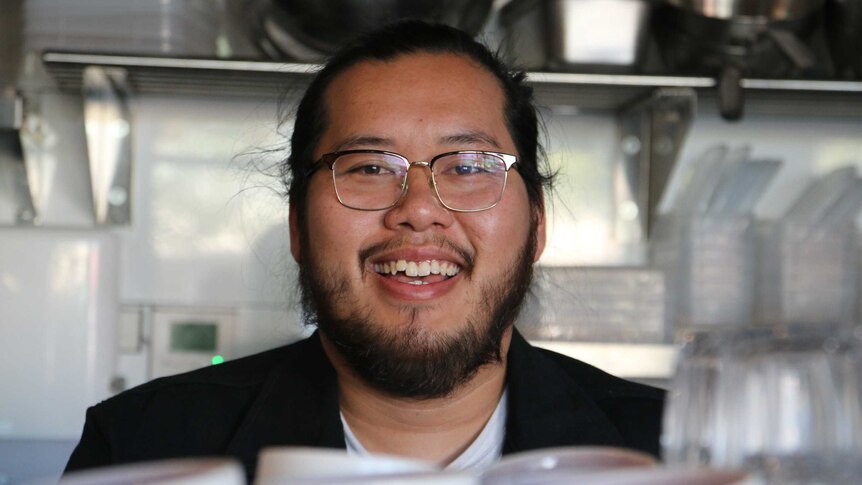 A man wearing glasses with a beard smiling at the camera