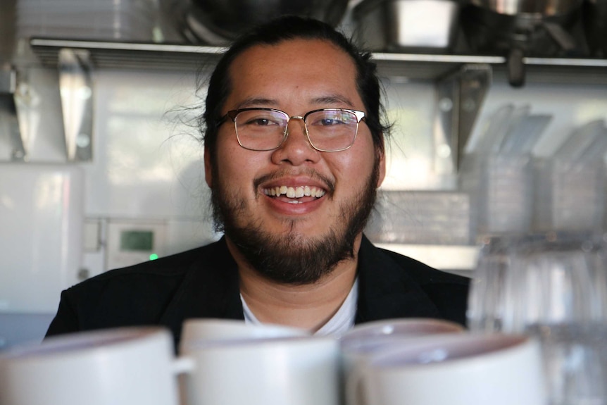 A man wearing glasses with a beard smiling at the camera