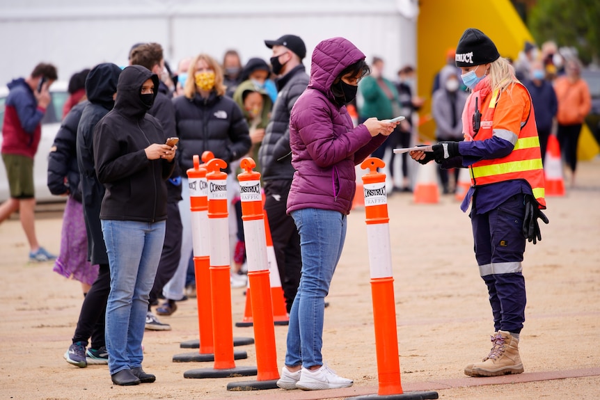 A woman scans a QR check-in code at a COVID testing site