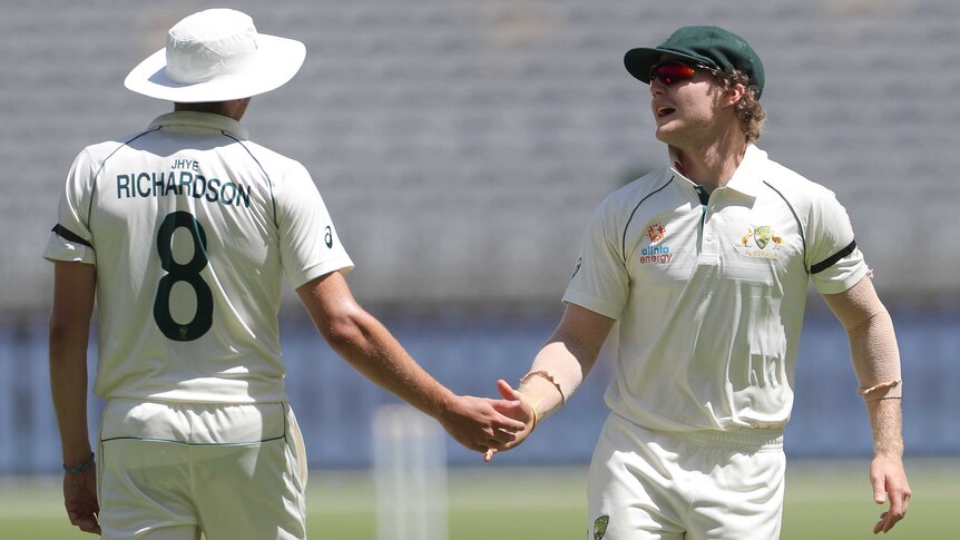 Two Australian A male cricketers shake hands during a match against Pakistan in Perth.