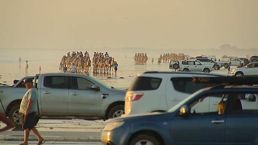Tourist riding camels and locals in cars make up a crowd on Cable Beach