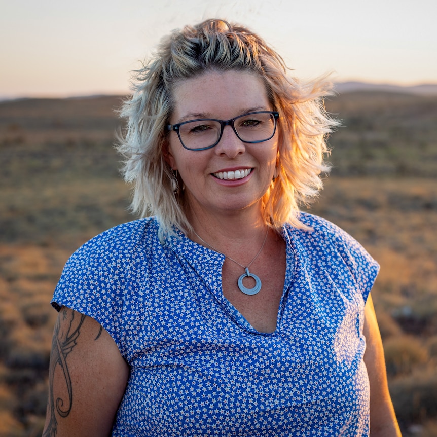 Presenter Kelly Gudgeon smiling at the camera with the sparse Pilbara landscape in the background