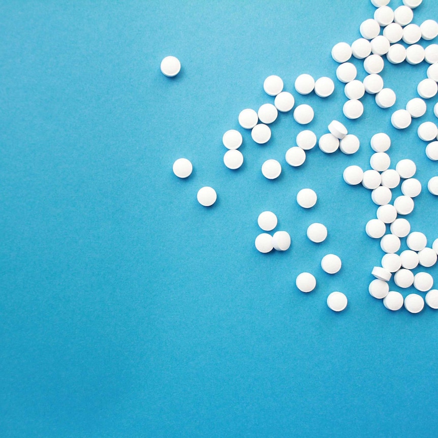 dozens of generic white tablets on blue background