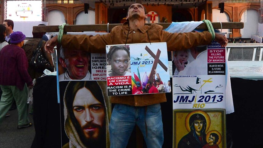 An activist ties himself to a crucifix and covers himself in posters