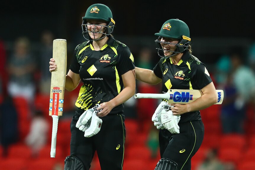 Two Australian female cricketers celebrate victory over India.