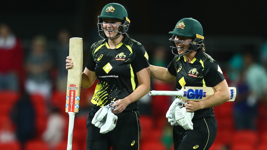 Two Australian female cricketers celebrate victory over India.