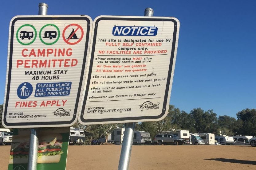 Camping permitted signs in foreground with caravans and mobile homes in background