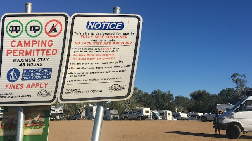 Camping permitted signs in foreground with caravans and mobile homes in background
