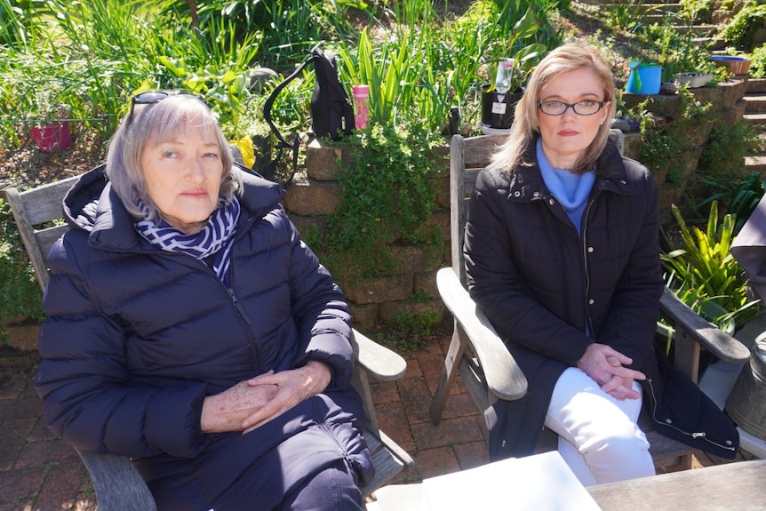 Two women, who are sitting outside, look at the camera