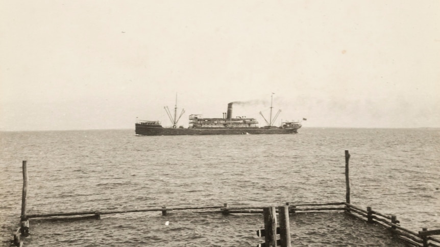 An historical black and white photo of the S.S. Mataram ship off the shore in Darwin Harbour.