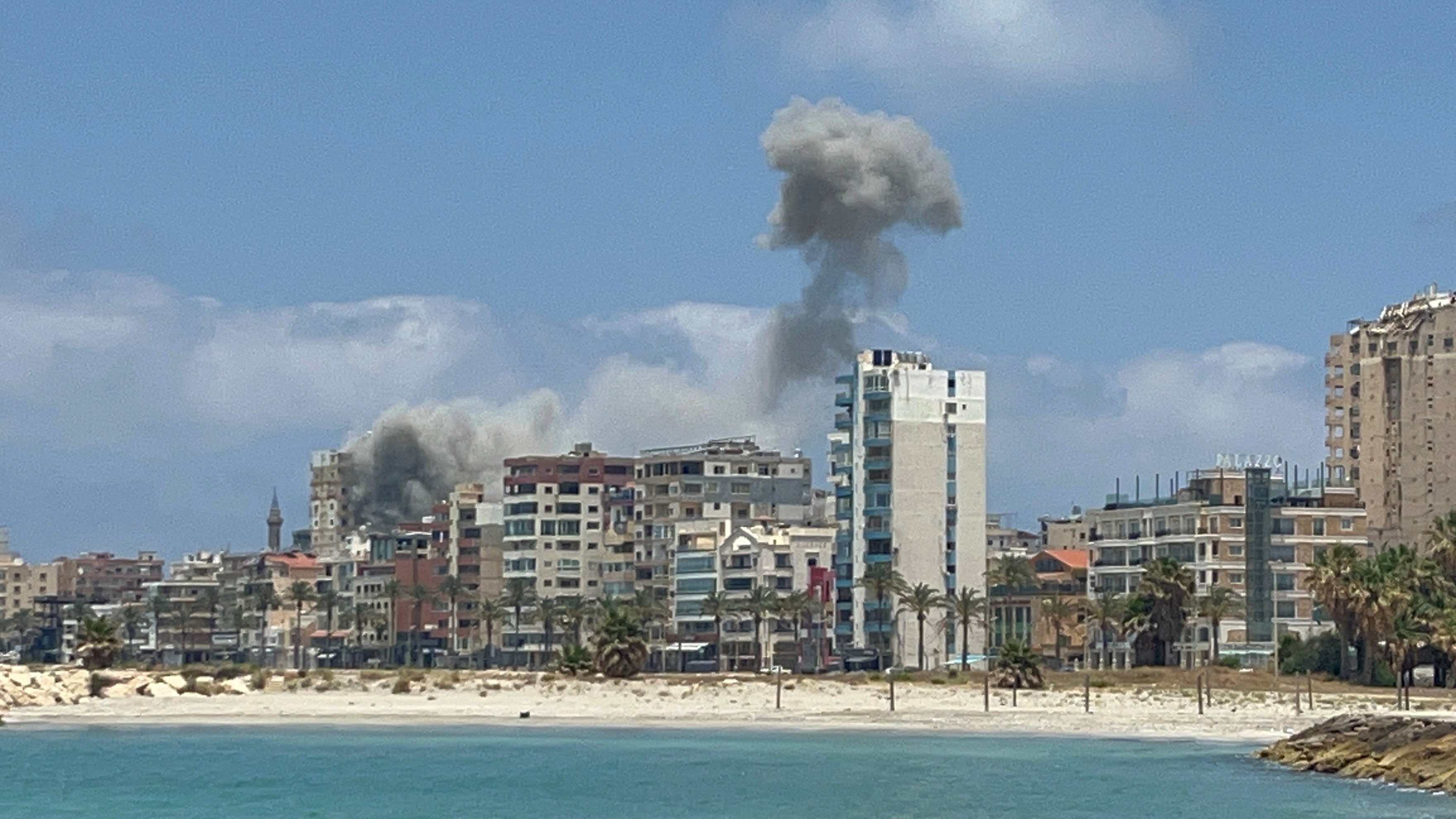 Smoke rises above a city on the coast.