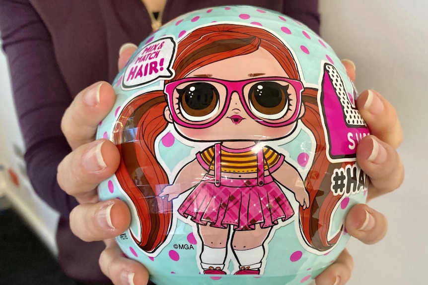 A hand-sized hard plastic ball with a cartoon drawing of a girl dressed in glasses and skirt and top.