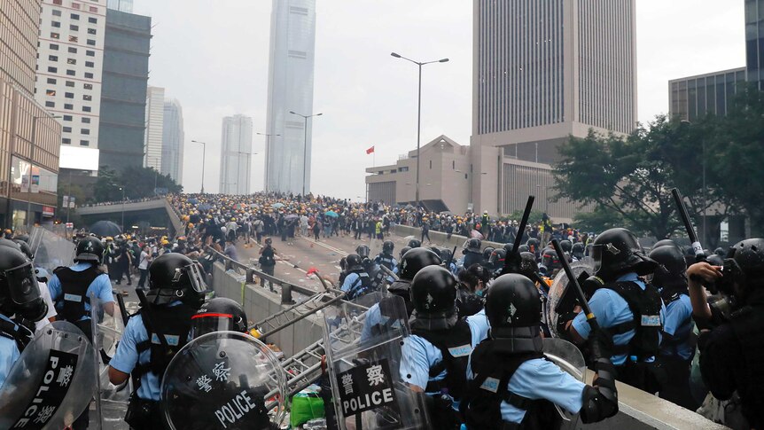 Riot police gather face off with demonstrators near the Legislative Council in Hong Kong, Wednesday, June 12, 2019. Hong Kong police fired tear gas and high-pressure water hoses against protesters who had massed outside government headquarters Wednesday in opposition to a proposed extradition bill that has become a lightning rod for concerns over greater Chinese control and erosion of civil liberties in the semiautonomous territory. (AP Photo/Kin Cheung)