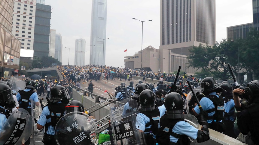 Looking down a raised expressway, Hong Kong police present a blockage to hundreds of protesters gathered further up the road.