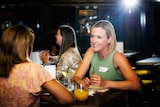 Two women talking in a bar at night