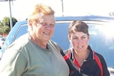 Dot Fox standing with her arm around her daughter Karen in front of her car outside on a sunny day.