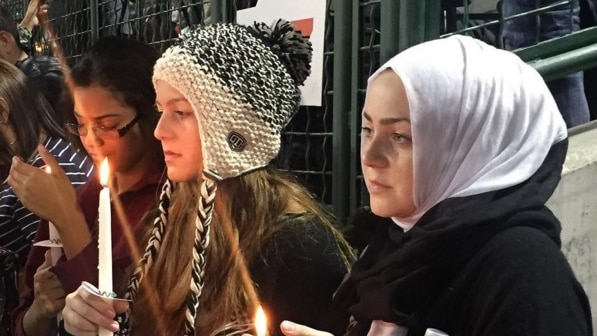 Mourners hold canldes.