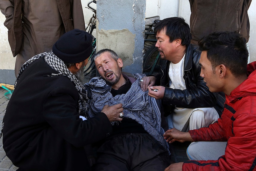 Several people care for a distraught man is cared for outside a hospital.