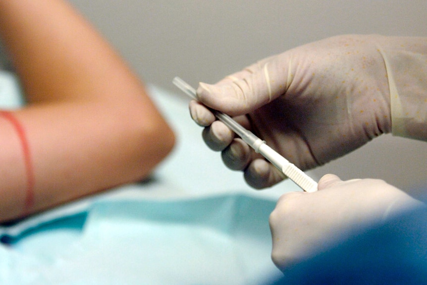 A nurse prepares an instrument used to insert a contraceptive implant