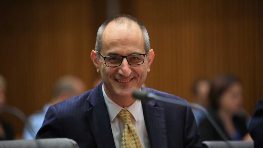 Michael Pezzullo smiles as he looks towards senators out of shot