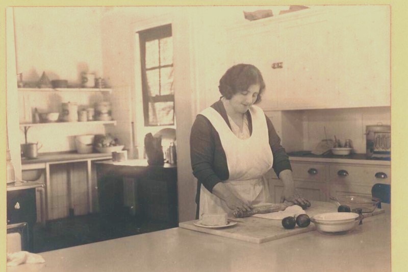 A woman cooks in an old fashioned kitchen