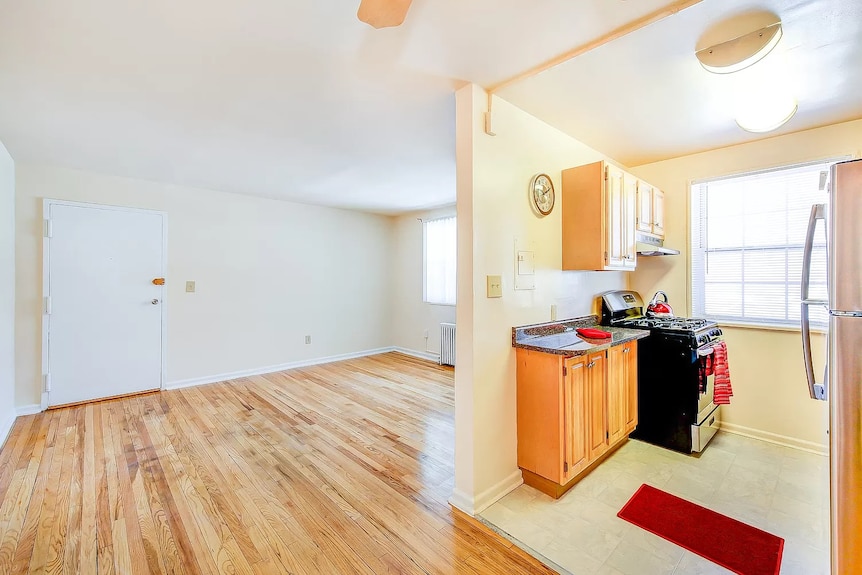 An empty apartment with a small open plan kitchen to the right of the photo. 
