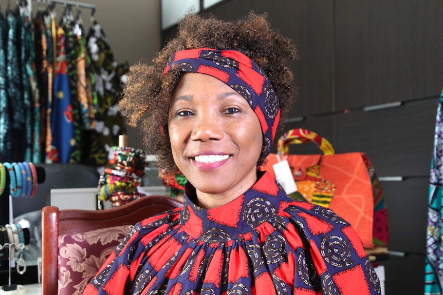 A woman wearing colourful clothing and a head scarf in headshot.