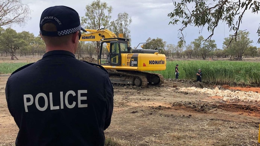 police overseeing an excavation in a large field