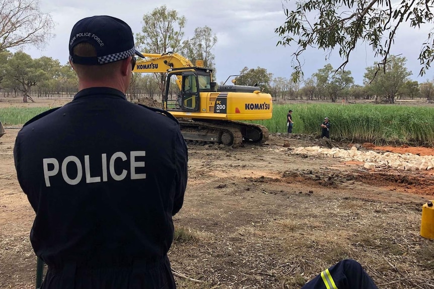 police overseeing an excavation in a large field