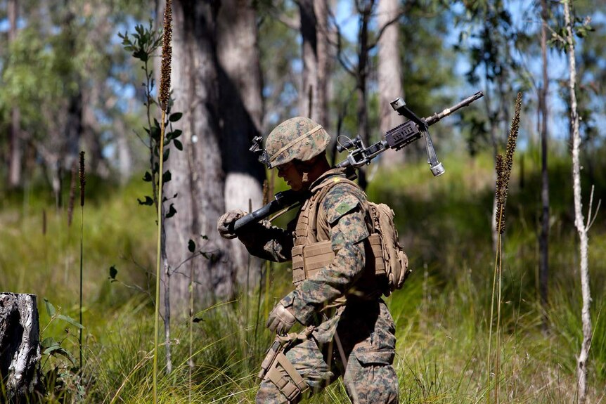 A US marine carries his rifle as he walks through bushland