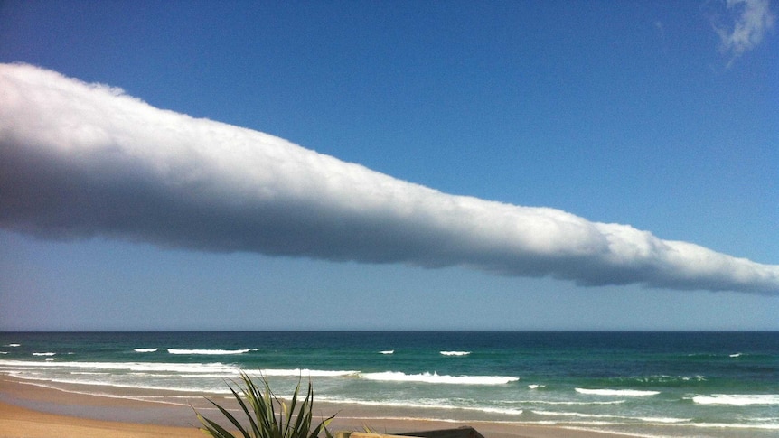 A roll cloud stretches into the distance over the ocean.