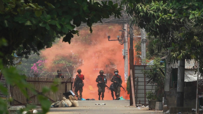 Three uniformed officers walk towards the camera. Behind them is a huge red cloud.