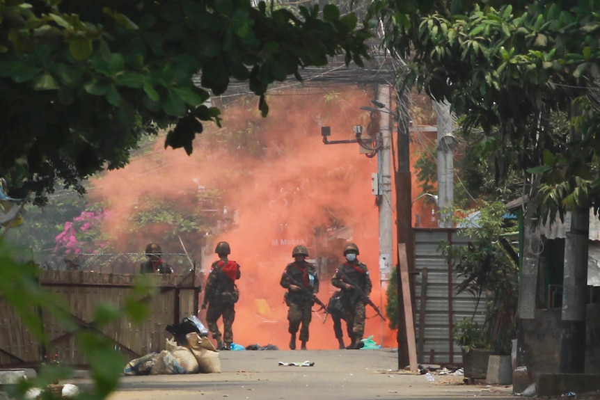 Three uniformed officers walk towards the camera. Behind them is a huge red cloud.