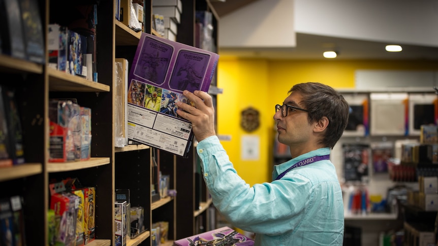 A man in a store filled with toys and boardgames.