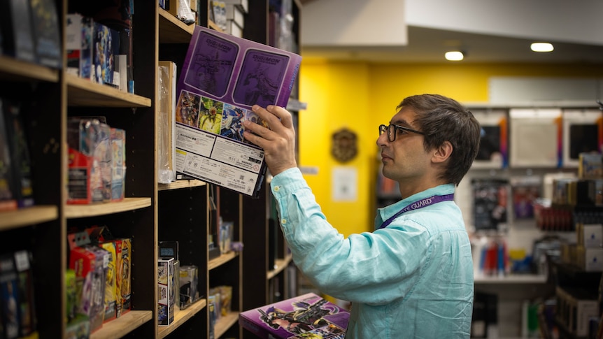 A man in a store filled with toys and boardgames.