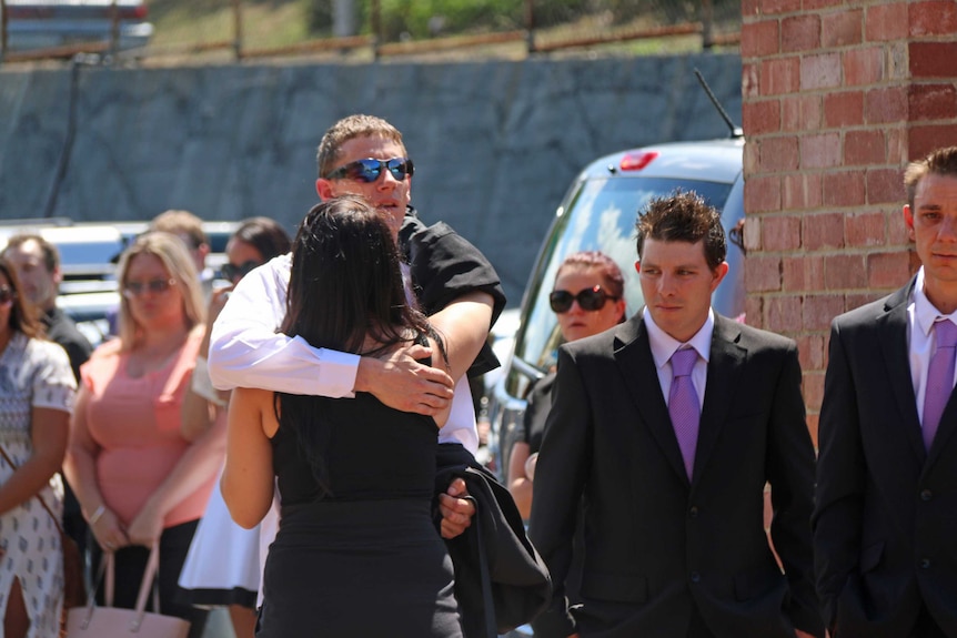 Mourners at the funeral of Hobart woman Sarah Paino comfort her partner Danial Stirling.