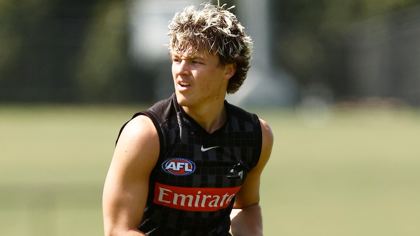 A Collingwood AFL player holds the ball at a training session in late 2022.
