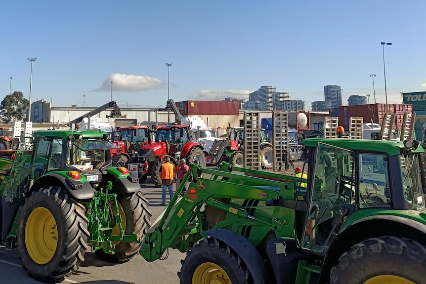 Numerous tractors parked in a yard in an inner-city area.
