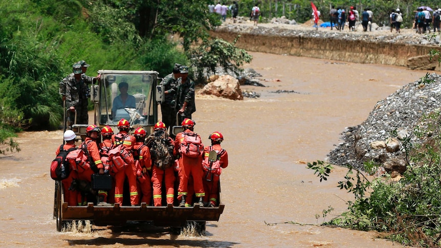 Rescue workers are transported into an earthquake zone on a front loader in Zhaotong in China's Yunnan province.