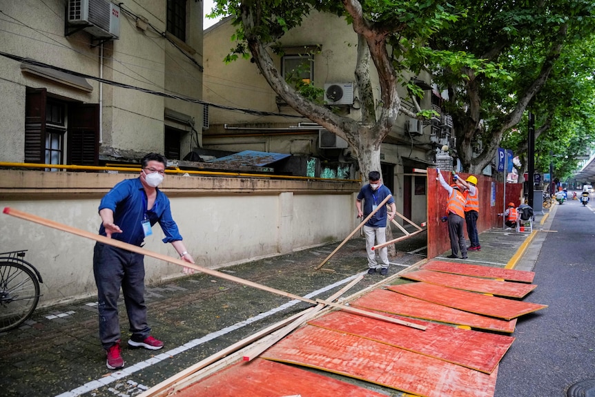 Workers dismantle barriers at a residential area, 