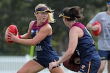 AFLW player high-fiving her teammate during training