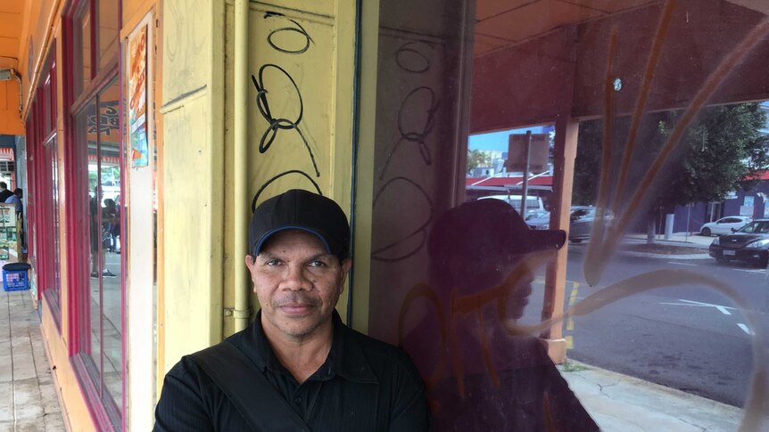 Cairns man Dezmond Green standing against a wall with graffiti